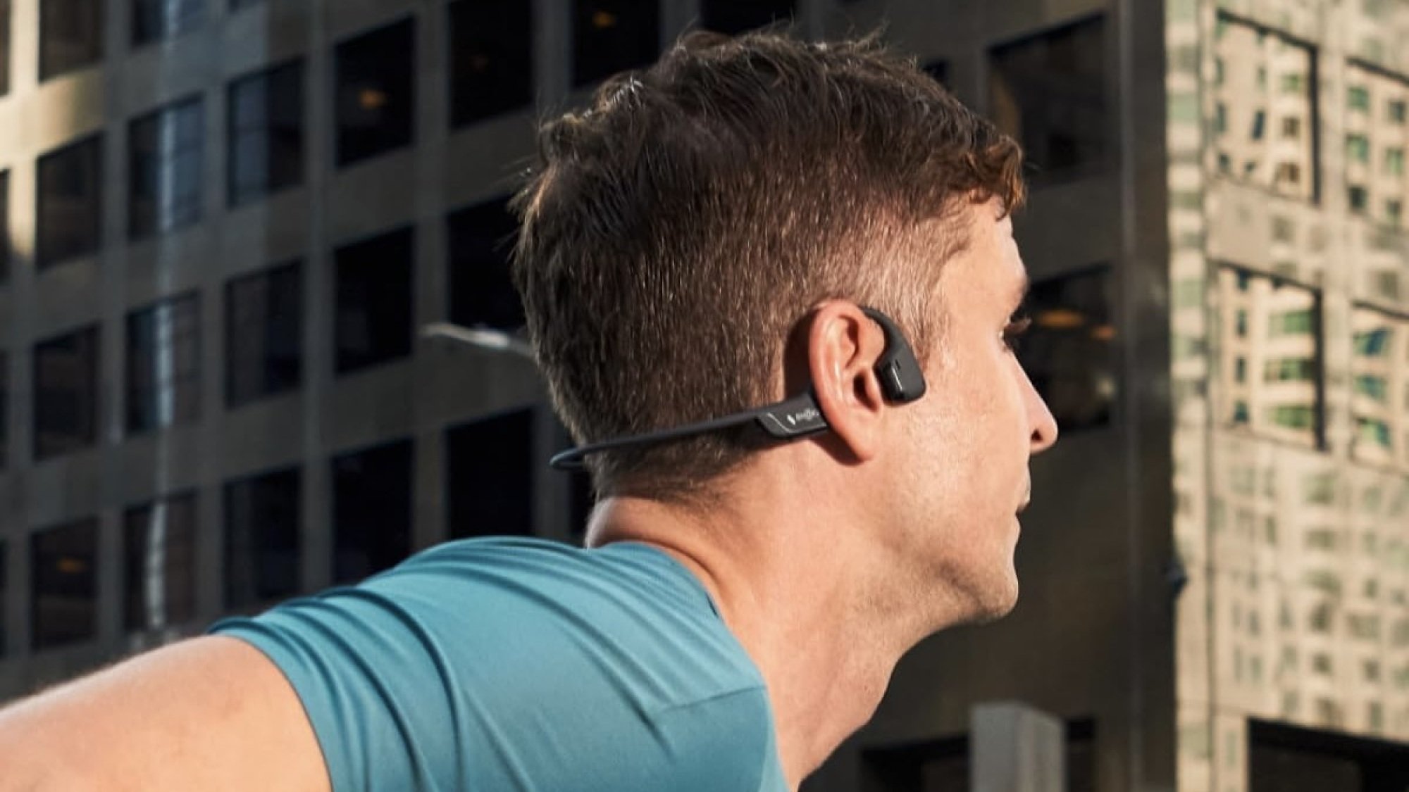 person running in a city wearing bone conduction earbuds